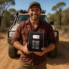 A person holding their Vehicle First Aid Kit while out in the bush, standing in front of their 4wd car